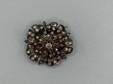 une broche en argent avec un diamant au centre, sur un fond blanc