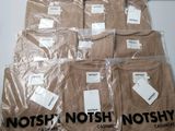six brown t - shirts are wrapped in plastic bags on a table