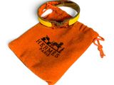 un sac orange orné d'un anneau, posé sur une surface blanche