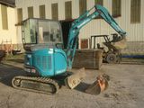 a blue excavator that is parked in front of a building