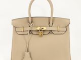 un sac à main en cuir beige muni d'un fermoir doré sur la poignée