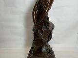 statue en bronze représentant une femme assise sur un rocher, les mains posées sur les genoux