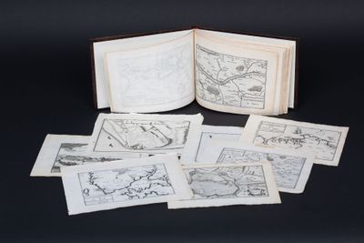 an open book sitting on top of a black table next to a pile of drawings