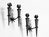 three black candle holders on a white wall next to each other