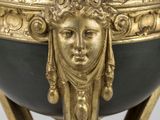 a gold and black vase with a face on it