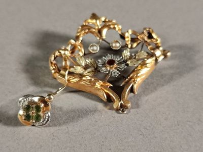 a gold brooch with green and white stones on it
