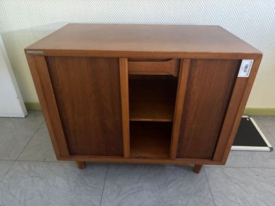 une photo d'une armoire en bois dont la porte est ouverte, posée à même le sol
