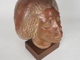 sculpture of a man ' s head on a wooden stand