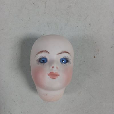 a small doll head with blue eyes on a white surface