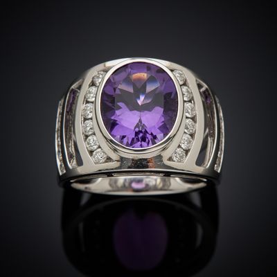 a close up of a ring with a purple stone surrounded by diamonds