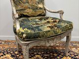 an old chair with a floral upholstered seat sits on a rug
