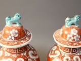 pair of orange and white vases with birds on top of them