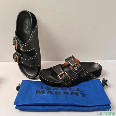 pair of black leather sandals with gold buckles and a blue cloth