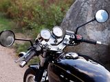 a close up of a motorcycle with a mirror and a rock in the background