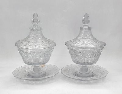 deux plats en verre transparent avec couvercles et soucoupes, posés sur un plan de travail blanc