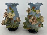 deux vases bleus ornés de fleurs, posés sur une surface blanche