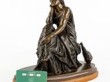 a bronze statue of a woman sitting on top of a wooden base