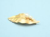 a gold leaf with a pearl on it on a blue surface