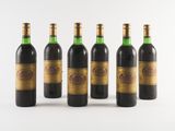 six bottles of wine are lined up on a white surface