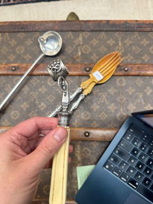 une personne tenant une cuillère et une fourchette devant un ordinateur portable