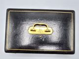 an old black suitcase with a gold handle sitting on a white surface