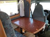 an image of the inside of a camper van with a table and chairs