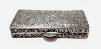 une vieille boîte en argent posée sur une surface blanche