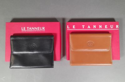 two black and brown leather wallets sitting on top of a pink box