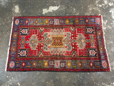 a red and blue rug sitting on top of a cement floor
