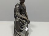 a bronze statue of a woman sitting on top of a table
