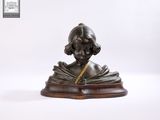 statue d'une femme en train de lire un livre, posée sur un socle en bois