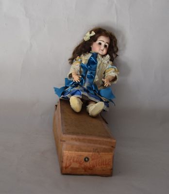 une petite poupée assise sur une caisse en bois