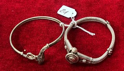 une paire de bracelets en argent posée sur un tissu rouge, avec une étiquette de prix