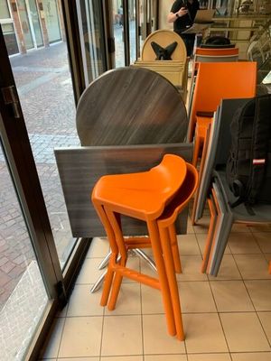 des tables et des chaises devant une fenêtre, avec une personne debout à l'arrière-plan