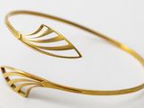 a close up of a gold cuff bracelet with a curved design