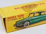a green toy car in a box on a white surface