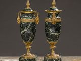 pair of green marble urns with gilded handles on a marble table