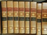several old books are lined up on a shelf in a library