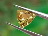 un gros plan d'un diamant jaune tenu par une pince
