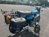 une moto bleue garée sur un parking, avec un panier à l'arrière