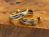 pair of gold and silver hoop earrings on a wooden surface