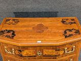 a small wooden chest of drawers on display on the floor