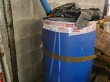 un fût bleu posé sur une palette à côté d'un mur de briques