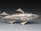 silver fish figurine on a gray surface with a black background