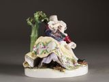 a figurine of a man and a woman sitting next to a tree