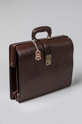 La mallette marron est posée sur une surface blanche sur laquelle est accrochée une étiquette.