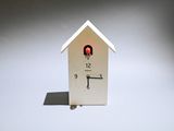 a white clock with a red light in the shape of a house