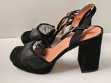 Les chaussures de cette femme sont noires et ornées de nœuds.