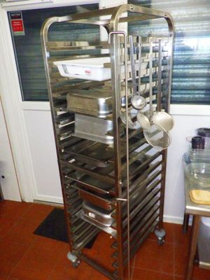 une étagère métallique sur laquelle sont posés de nombreux plats, dans une cuisine