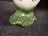 a green vase sitting on a table with a black background